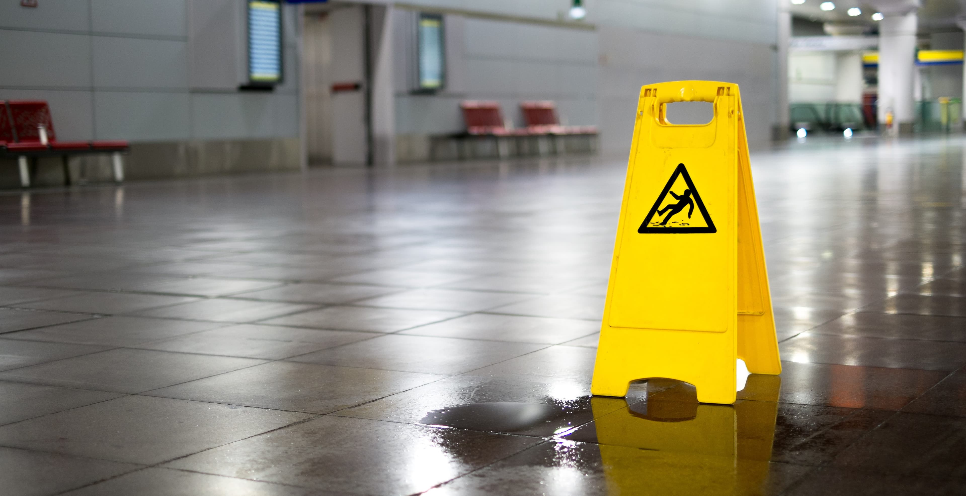 Yellow caution wet floor sign placed on top of water on the floor. | Personal Injury | The Sullivan Law Firm